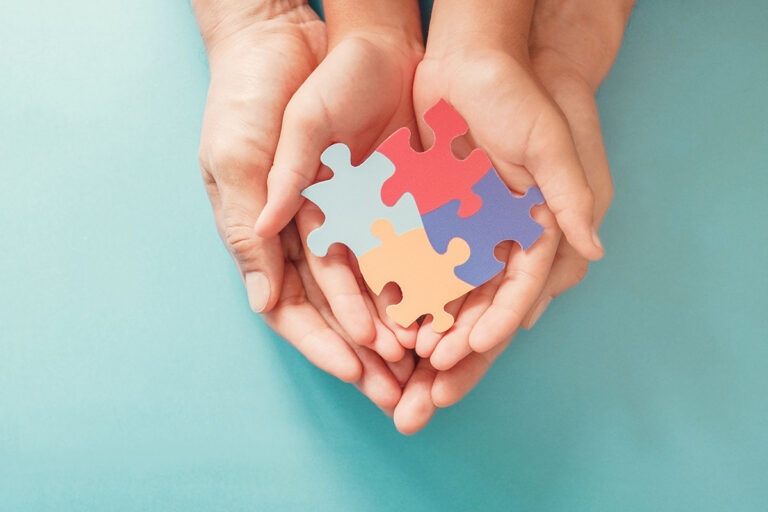 hands of an adult holding hands of a child holding colorful puzzles