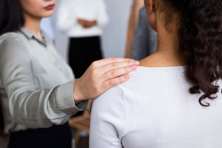 Woman comforting another girl while touching her shoulder