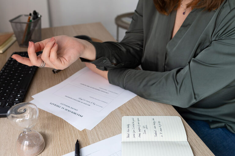 Woman taking notes in a notebook on a desk while reading some documents