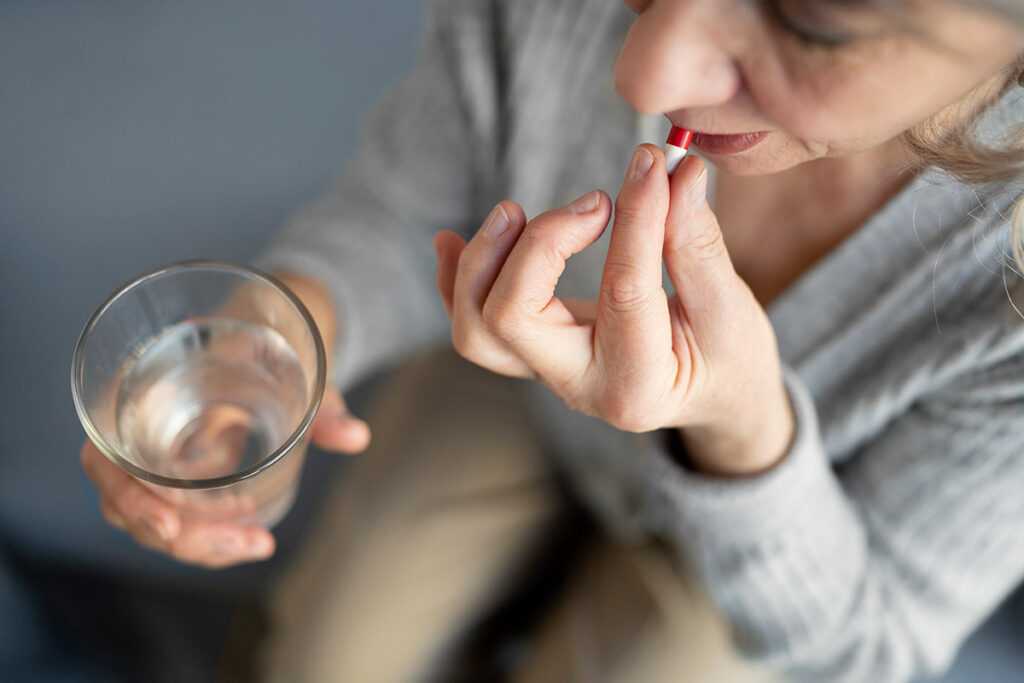 Woman taking a pill while holding a glass of water